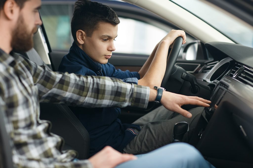 Shot of a young boy talking to his cheerful father sitting together in a new car driving travelling trip journey happiness lifestyle parent vehicle automobile rent safety insurance family parenting